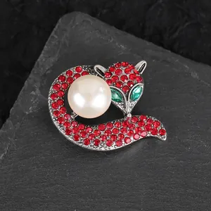 Macro detail of fox brooch featuring red rhinestones, green crystal eyes and white pearl
