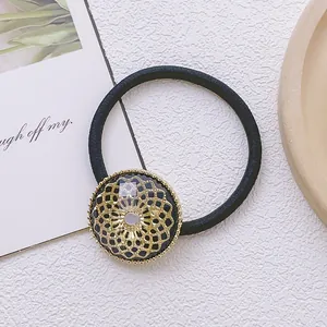 Détail du motif fleur dorée avec cristal sur un élastique à cheveux noir robuste