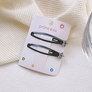 Detalle de dos pinzas negras para el pelo con motivo floral de diamantes sobre tarjeta blanca
