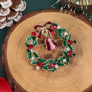 Détail de la broche couronne de Noël avec nœud rouge et cloches sur fond de pommes de pin