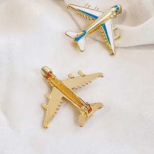 Vues avant et arrière d'une broche avion en émail bleu et blanc sur tissu soie