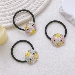 Lot de trois chouchous élastiques avec fleurs et strass sur fond texturé blanc