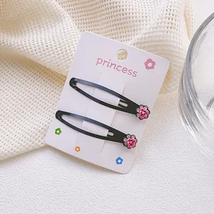 Detalle de pinzas de metal negro con rosas rosas en una tarjeta de exhibición princess