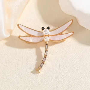 Élégante broche libellule dorée avec ailes en nacre rose et corps orné de zircons brillants