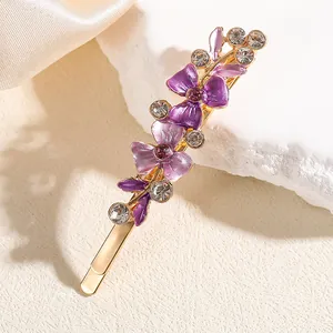 Dettaglio del fermaglio dorato con fiori viola e brillanti strass in cristallo puro