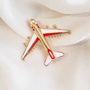 Broche avion moderne dorée avec émail rouge et blanc sur tissu en soie blanche