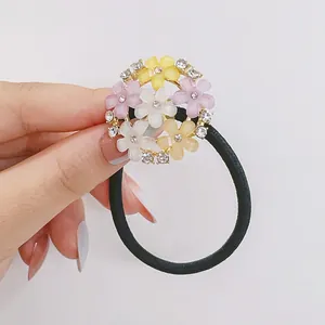 Détail d'un élastique à cheveux avec fleurs en strass aux couleurs pastel douces