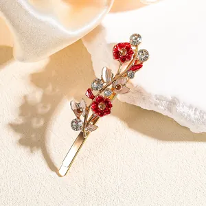 Dettaglio del fermaglio a fiore con petali in smalto rosso, foglie d'oro e cristalli
