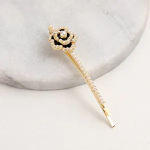 Elegant pearl camellia hair clip with black floral design and crystals in gold setting