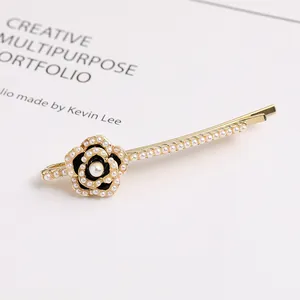 Elegant pearl camellia hair clip with black enamel finish and gold crystal accents