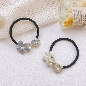 Détail de chouchous fleurs avec centre en strass, perles et pétales en émail coloré