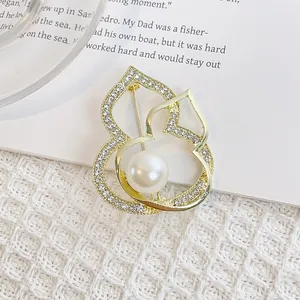 Détail macro d'une broche hulu dorée avec des strass étincelants et une grande perle