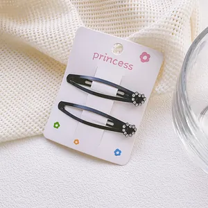 Detalle de dos pinzas para el cabello de metal negro con corazones de strass brillantes