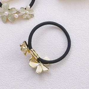 Détail d'un élastique à cheveux avec fleurs en émail, perles et strass brillants