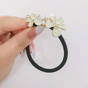 Détail d'élastique à fleurs avec pétales en émail vert, perles blanches et cristaux brillants