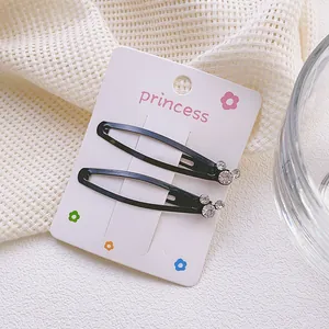 Detalle de pinzas para el pelo negras tipo gota con strass en tarjeta de presentación