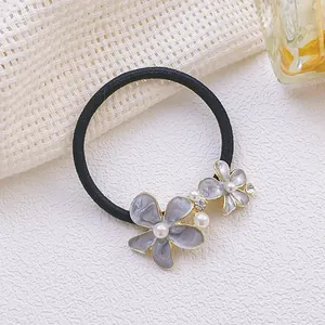 Gros plan sur l'élastique à cheveux fleuri avec strass gris-violet, perles et métal doré