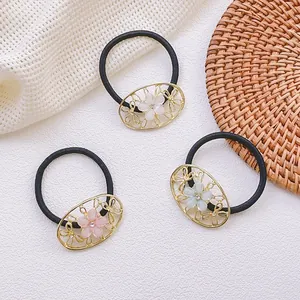 Vue détaillée de trois élastiques à cheveux fleurs avec strass sur fond de dentelle