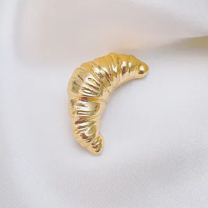 Detailed macro view of the golden croissant brooch with vintage twisted texture on white silk