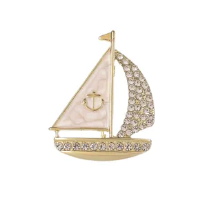 Elegante spilla a forma di barca a vela dorata con vele in smalto e strass brillanti