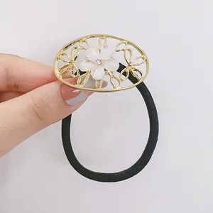 Détail de l'élastique fleur avec base dorée ajourée, pétale blanc et petit strass