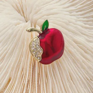 Sparkling red apple brooch with green leaf and rhinestone detail on elegant background