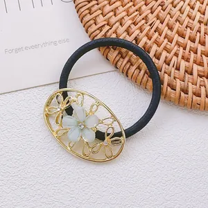 Gros plan d'un élastique à cheveux noir avec cadre floral doré et strass vert scintillant
