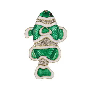 Broche de pez tropical dorado con esmalte verde y cristales brillantes en fondo blanco