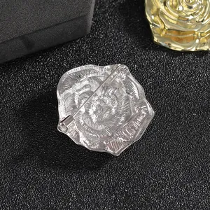 Polished silver rose brooch with secure pin back on a dark textured background