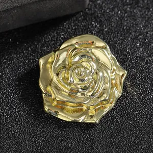 Detailed macro shot of a 3D gold rose brooch with layered petals on a black background