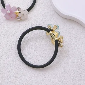 Détail d'élastiques à cheveux avec fleurs en résine, perles et strass sur fond blanc uni