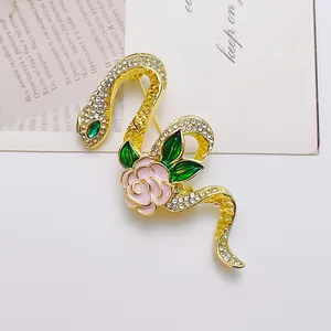 Broche de serpiente dorada con escamas de cristal, rosa de esmalte rosa y hojas verdes finas