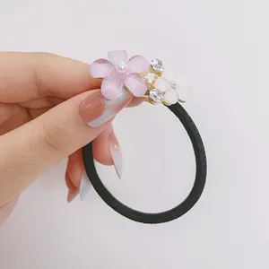 Gros plan sur élastique à cheveux fleur avec pétales violets et strass scintillants