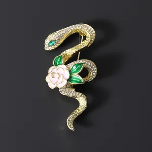 Broche de serpiente y rosa dorada con cristales blancos y hojas de esmalte verde