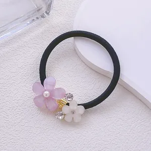 Détail d'un élastique à cheveux avec fleurs en strass et centre en perles