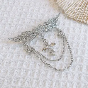 Détail d'une broche rétro argentée avec cœur ailé, chaînes multicouches et croix sertie