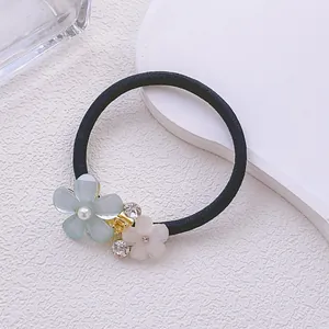 Gros plan détaillé du chouchou à fleurs en strass avec perles et pétales mats rose et bleu