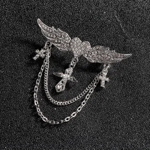 Détail de la broche ailes d'ange avec cœur et chaînes à croix ornées de strass argentés