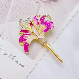 Elegante spilla a fiore di giglio con smalto rosa e cristalli su sfondo libro vintage