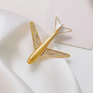 Gold airplane brooch with white rhinestones and Good Luck engraving on silk
