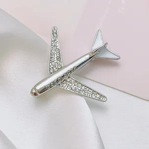 Close-up of a silver airplane brooch with white rhinestones and enamel on silk