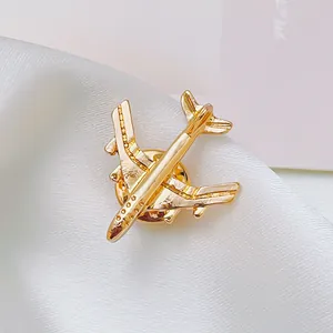 Close-up of golden airplane brooch showing fine metallic details on white satin