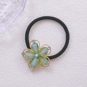 Détail d'un élastique à cheveux avec breloque fleurie en strass dégradé et bords dorés