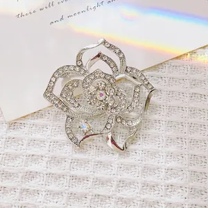 Broche rose argentée raffinée avec strass scintillants sur fond en tweed élégant