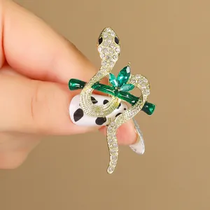 Retro gold snake brooch with sparkling rhinestones and green enamel accents on branch