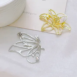 Broches élégantes fleur dorée et papillon évidé argenté sur fond de tissu blanc