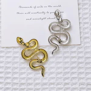 Snake brooch set in gold and silver finish with detailed pin fastener on waffle fabric