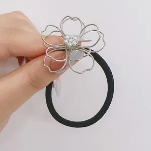 Gros plan d'un élastique à cheveux fleur argentée avec perles blanches et ruban noir