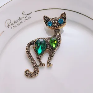 Vintage cat brooch in bronze gold with green crystal teardrop gems and blue eyes