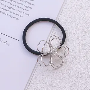 Détail d'un élastique à cheveux fleur en métal argenté avec perles blanches et bande noire